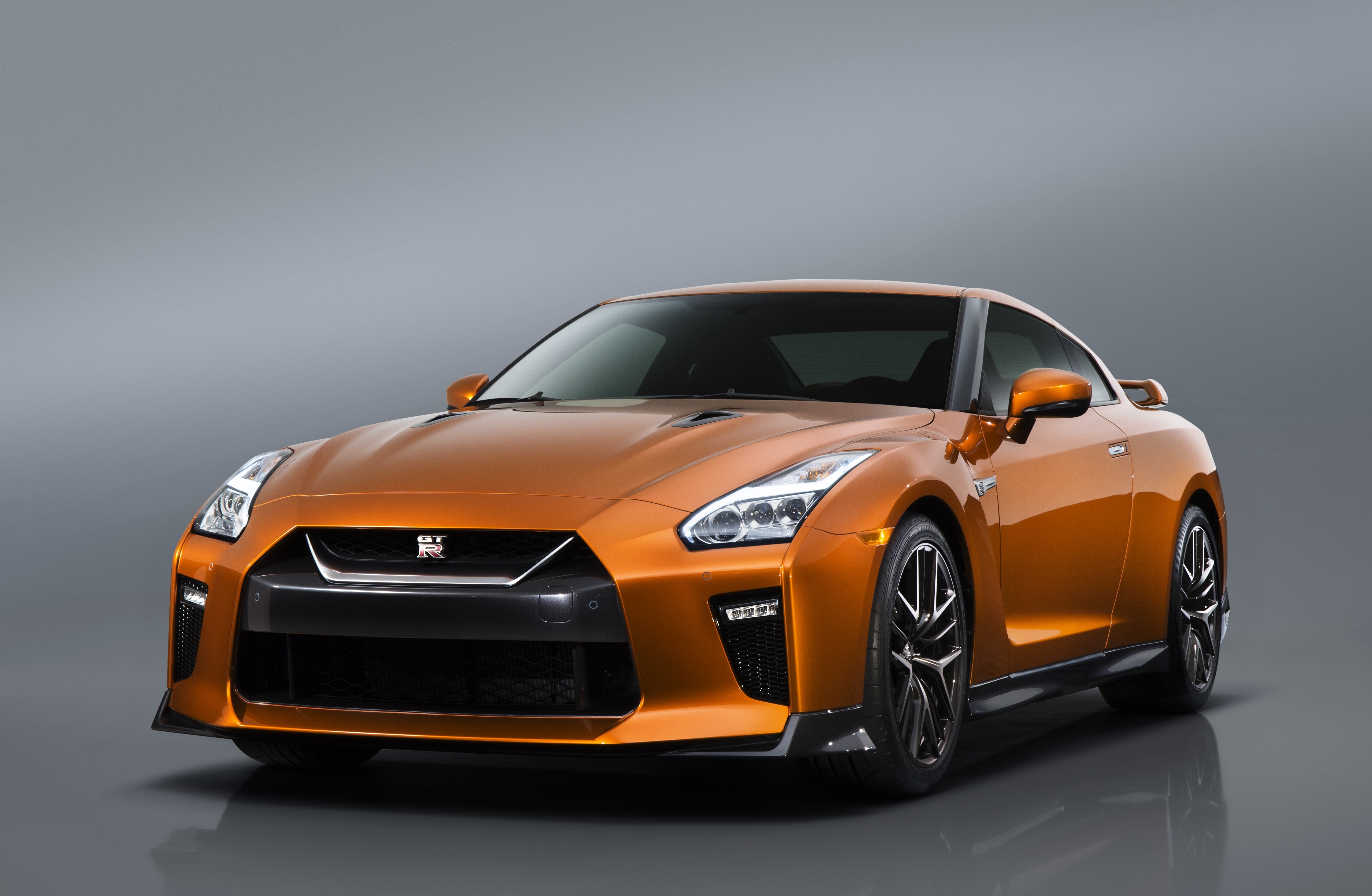 The 2017 GT-R's exterior receives a thorough makeover. The new "V-motion" grille, one of Nissan's latest design signatures, has been slightly enlarged to provide better engine cooling and now features a matte chrome finish and an updated mesh pattern. A new hood, featuring pronounced character lines flowing flawlessly from the grille, has been reinforced to enhance stability during high-speed driving. A freshly designed front spoiler lip and front bumpers with finishers situated immediately below the headlamps give the new GT-R the look of a pure-bred racecar, while generating high levels of front downforce.